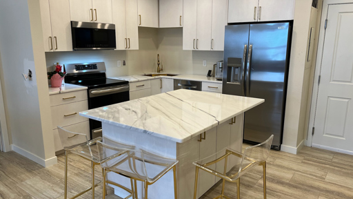 a kitchen with a marble counter top and gold stools