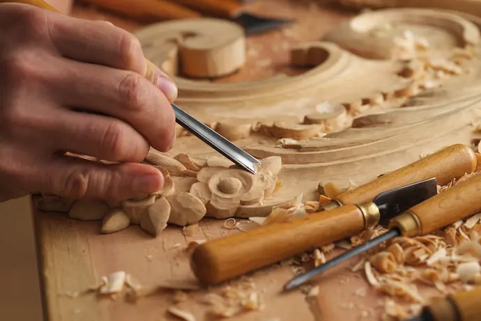 man hand carving finishing touches on cabinets