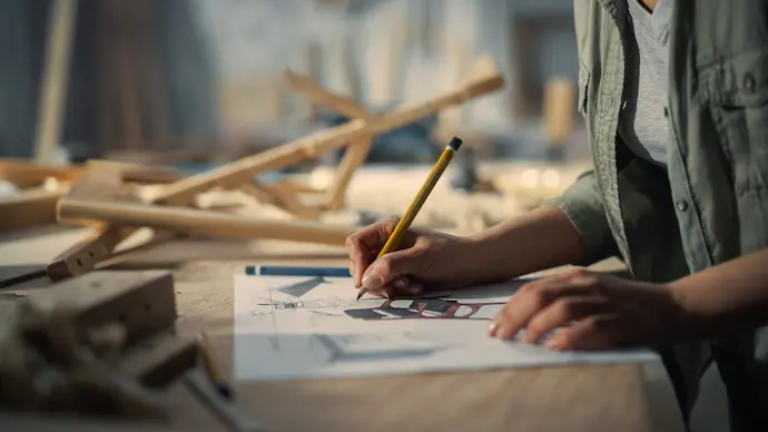 man drafting a design onto a sheet of paper for woodworking project