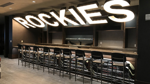 a bar with stools and a sign that says rockies