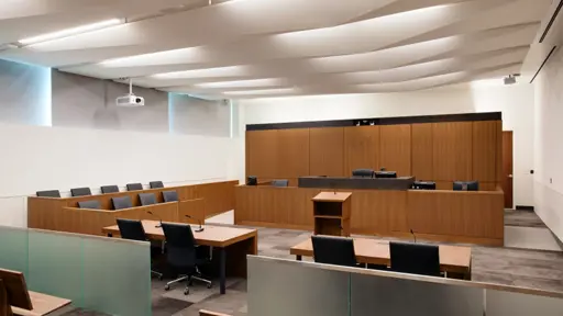a courtroom with wooden benches and a glass wall