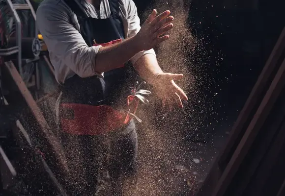 man covered in saw dust leaving a workshop